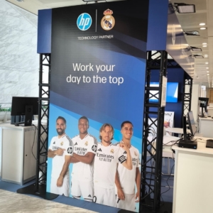 El stand conjunto de los partners en el Congreso & EXPO ASLAN 2025, incluyendo a Foqum y otras marcas tecnológicas, con el sorteo de tres camisetas del Real Madrid entre los visitantes, destacando la colaboración y la innovación del evento.