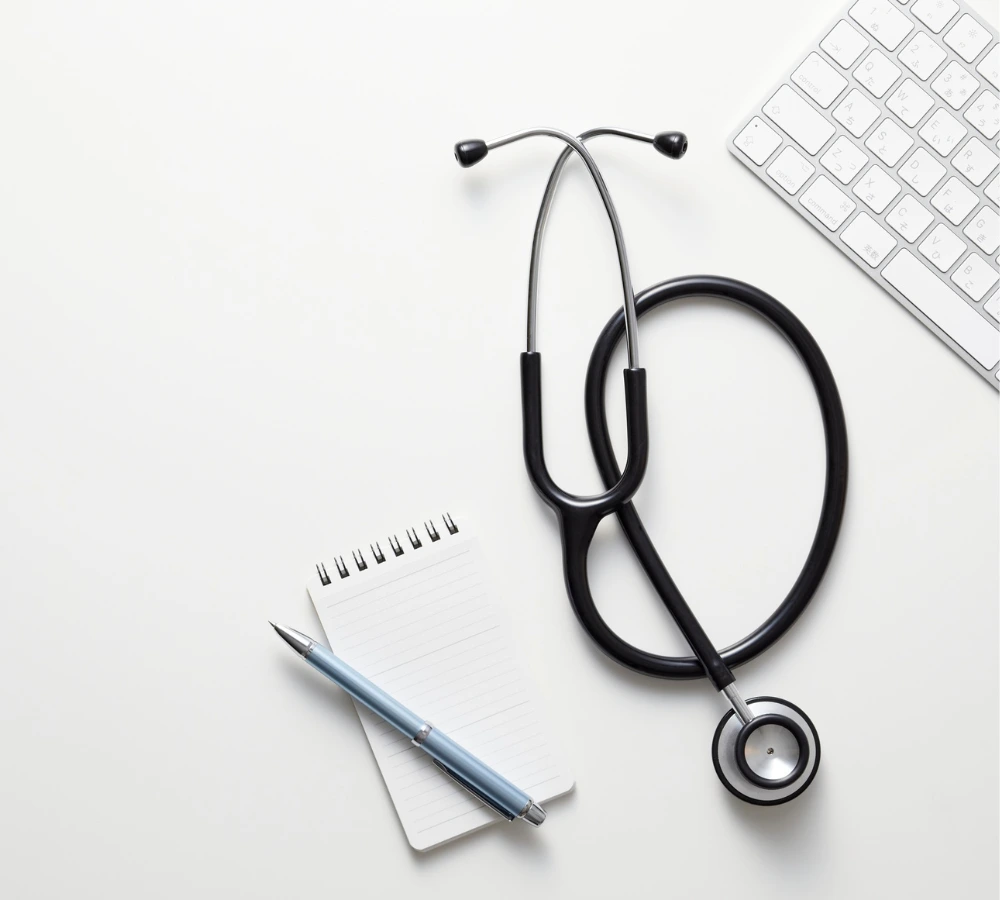 Vall dhebron interna 1 Un estetoscopio, un cuaderno y un teclado sobre una mesa blanca. Representación de la convergencia entre la medicina tradicional y la tecnología de ia agéntica para la normalización de datos.
